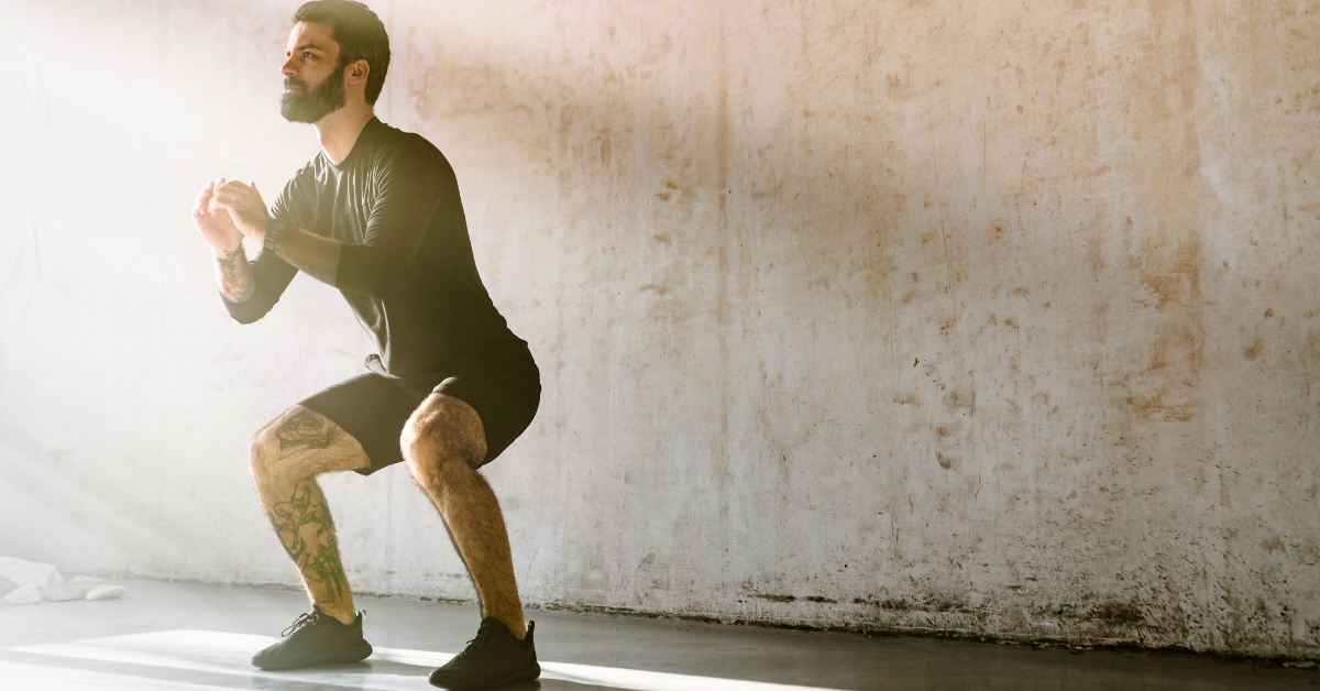 physically fit man squatting early morning