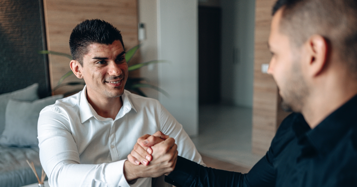 two men shaking hands and smiling at each other