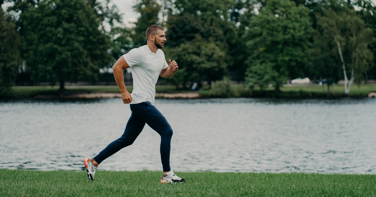 mid age man jogging with a lake background